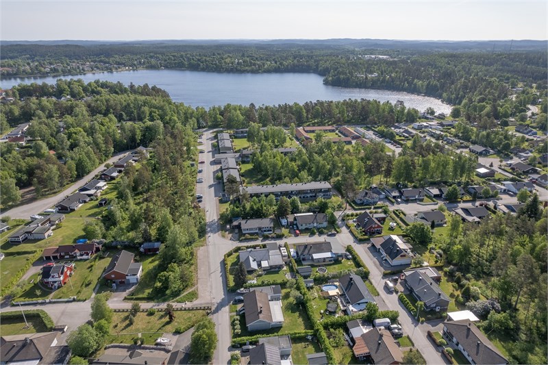 Drönarbild med vy över hus med sjön baktill.